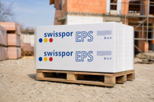 Płyty styropianowe EPS100 Swisspor na palecie w otoczeniu placu budowy, widoczny logotyp na opakowaniu.