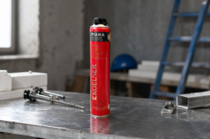 Korpus puszki pianki montażowej Koelner 750 ml na stanowisku warsztatowym w realistycznym otoczeniu budowlanym, z lekko rozmytym tłem narzędzi i materiałów.